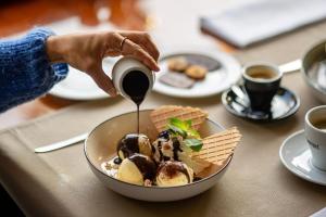 a person is pouring sauce into a bowl of food at Hôtel-Restaurant L'Auberge in Spa +17 photos