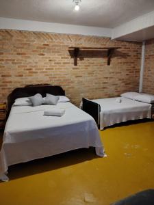 a bedroom with two beds and a brick wall at Catavento Flats e Suítes in Maresias