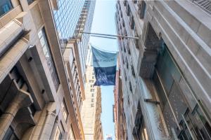 a flag hanging between two buildings in a street at Mint House 70 Pine by Kasa in New York