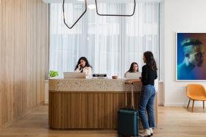 two women sitting at a reception desk with their laptops at Mint House 70 Pine by Kasa in New York