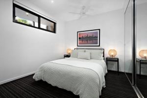 a white bedroom with a bed and two windows at A tale awaits - just steps from trendy cafés and lively bars in Melbourne