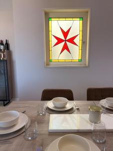 a table with plates and glasses and a stained glass window at Panoramic View Penthouse With Dual Terraces in Xagħra