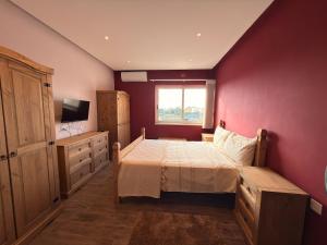 a bedroom with a bed and a red wall at Panoramic View Penthouse With Dual Terraces in Xagħra
