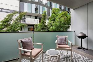 two chairs and a table on a balcony with a building at A tale awaits - just steps from trendy cafés and lively bars in Melbourne