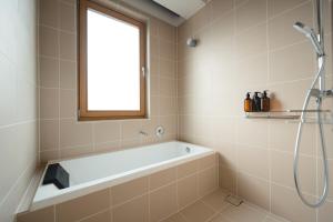 a bathroom with a bath tub and a window at KOTOBUKI Hotel in Kanoya +65 photos