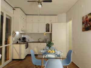a kitchen with a table and blue chairs and a kitchen with white cabinets at P & G Apartment in Pámfylla