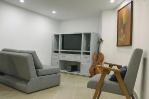 a living room with two chairs and a television and a violin at Casa Centenario in Taxco de Alarcón