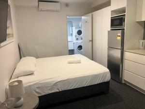 a small room with a bed and a refrigerator at Bondi Beach Studios Suite in Sydney