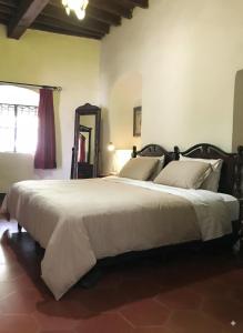 a bedroom with a large white bed with a mirror at Casa Centenario in Taxco de Alarcón