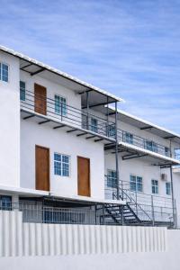 a white building with wooden doors and a fence at Habitaciones amobladas - Manabí suites in Manta