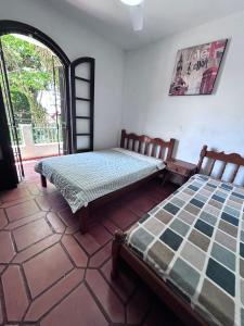 two beds in a room with a window at Casa espaçosa 100m da praia in Ubatuba