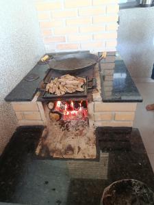 a brick oven with a grill with food inside at Casa Aconchegante com Espaço Gourmet in Itatiba
