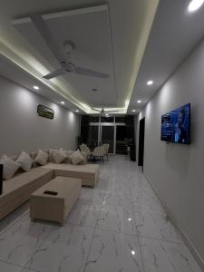 a living room with a couch and a tv on a wall at Elite Corners Luxury 2BR Apartment The Gate Mall Faisal Town in Barkat