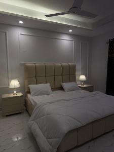 a bedroom with a large bed with two night stands at Elite Corners Luxury 2BR Apartment The Gate Mall Faisal Town in Barkat