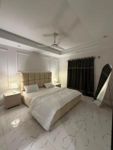 a bedroom with a large white bed and a ceiling at Elite Corners Luxury 2BR Apartment The Gate Mall Faisal Town in Barkat
