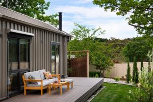 a backyard deck with a couch and a table at Piccola Verde Tiny House in Hepburn