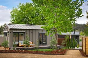 a small shed with a table and chairs in a garden at Piccola Verde Tiny House in Hepburn