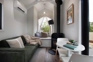 a living room with a couch and a table at Piccola Verde Tiny House in Hepburn +1 photo