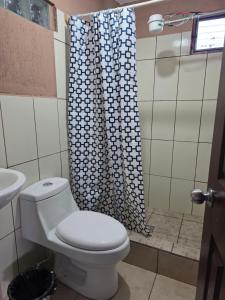 a bathroom with a toilet and a shower curtain at Hotel Fontana Real in Quetzaltenango +12 photos