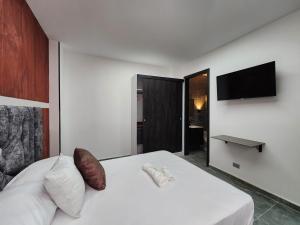 a bedroom with a white bed and a flat screen tv at Apartamentos Batara in Filandia