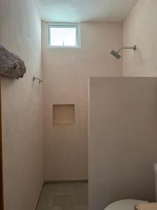 a bathroom with a toilet and a window on the wall at Habitat in Barra de Navidad +24 photos