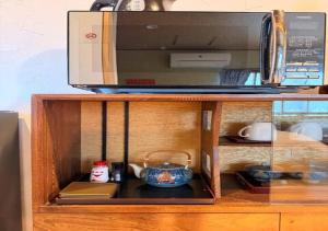 a cabinet with a microwave on top of it at 京都 大阪アクセス良好の和モダン民泊 静かで快適な宿泊施設です 京阪本線楠葉駅から徒歩圏内 急行特急停車駅で京都へ約30分 大阪へ約40分とアクセス良好です in Hirakata
