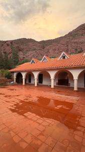 a building with a red roof with a mountain in the background at The Baron House in Tupiza