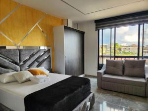 a bedroom with a bed and a couch and a window at Apartamentos Batara in Filandia