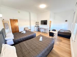a hotel room with two beds and a desk at Alpine Heritage Motel in Goulburn