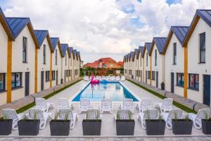 a pool with white chairs and a row of buildings at Holiday homes with pool, close to the beach in Rewal