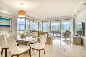 a dining room with a table and chairs and windows at Sea Pearl A1 Beach Resort in Mooloolaba