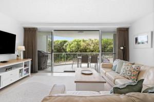 a living room with a couch and a tv and a table at Unit 2 Point Break in Yaroomba