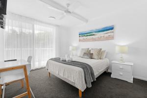 a white bedroom with a bed and a desk at Unit 2 Point Break in Yaroomba +11 photos