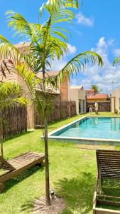 a palm tree next to a swimming pool at VILA GAHERI Pousada Boutique com Piscina Privativa in São Miguel dos Milagres