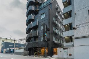 a tall black building on the side of a street at BAKURO - Doyanen Hotels in Osaka