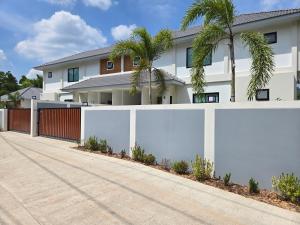 a white fence in front of a house with palm trees at Vanesa Serenity Villa 1 in Ban Chong Phli