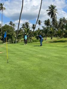 two people playing golf on a green with palm trees at AT ONE - with Nature Glamping, Rekawa in Tangalle
