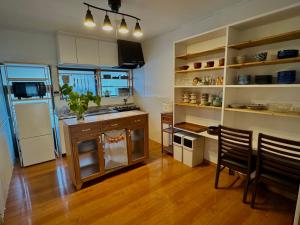 a kitchen with a refrigerator and a table and chairs at 愛犬と泊まれる宿 ほこほこsaza 一棟貸し 海も川も徒歩圏内 dog run付き 釣りの穴場 サーフィン 自然 満点星空 蛍鑑賞 最大7名 in Miyazaki +28 photos