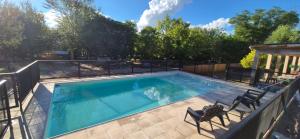 a swimming pool with two chairs and a fence at Casa Playa Mansa in Mina Clavero