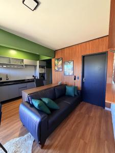 a living room with a black couch and a kitchen at Apartamento COMPLETO- Próximo ao shopping JL in Cascavel