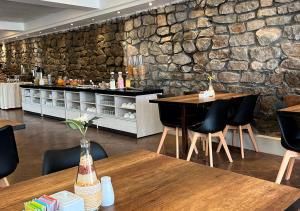 a restaurant with wooden tables and a stone wall at Hotel La Villa Mollendo in Mollendo