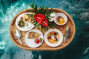a tray with plates of food on top of a pool at Jellyfish Villas Bingin, Uluwatu in Uluwatu