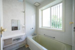 a bathroom with a bath tub and a window at villa itsutsu in Kamigotō +91 photos