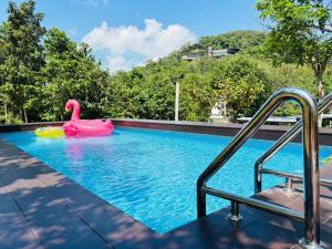 a swimming pool with a pink swan in the water at Greenery Hill in Ban Nok