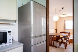 a kitchen with a stainless steel refrigerator and a table at villa itsutsu in Kamigotō