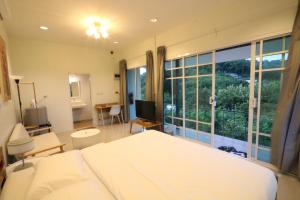 a bedroom with a bed and a large window at Greenery Hill in Ban Nok +27 photos