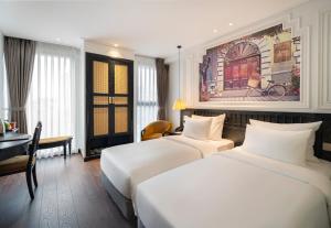 a hotel room with two beds and a desk at Luxe Paradise Suites Hotel & Spa in Hanoi
