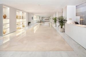 an empty hallway with white walls and floors and plants at Melia Lebreros in Seville