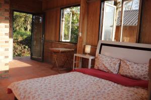 a bedroom with a bed and a balcony with windows at Midori Heritage Coffee Farm in Da Lat