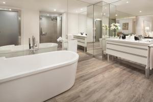 a white bathroom with two sinks and a tub at Melia Lebreros in Seville